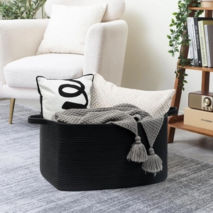 Detail of a large black cotton rope storage basket holding cozy blankets and pillows