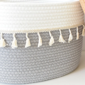 Detail of woven cotton rope basket featuring grey two-tone design and beige tassel fringe