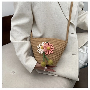 Detail of hand-woven straw crossbody bag with 3D pink and white crochet flowers