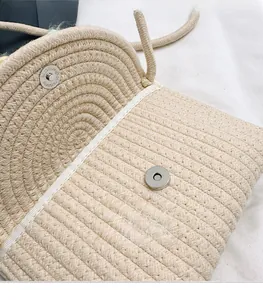 Detailed macro view of woven cream shoulder bag featuring silver magnetic snap closure