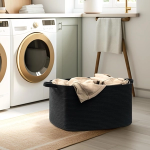 Detailed view of black woven cotton rope laundry basket with handles in a laundry room