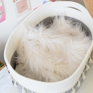 Detail of hand-woven cotton rope storage basket with tassel charm and gray contrast trim