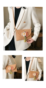 Detail of hand-woven straw crossbody bag with floral accents and textured fiber pattern