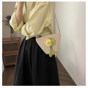 Détail d'un sac seau en coton tressé avec fleurs 3D porté à l'épaule par un mannequin