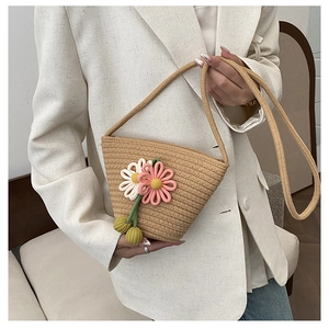 Close-up of handmade woven straw bag with decorative 3D floral accents and strap detail