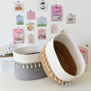 Close-up of woven cotton rope storage baskets with decorative white fringe in a home setting