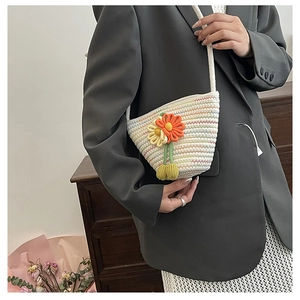 Detail of hand-woven crossbody bag with vibrant 3D floral crochet on a beige texture