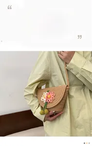Close-up of handmade woven straw bag with pink crochet flowers and green pendant details