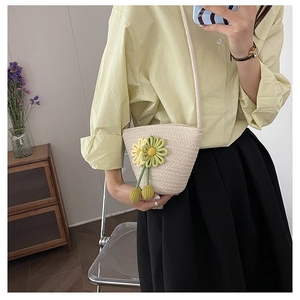 Detail of straw woven crossbody bag with colorful 3D flower decor on yellow knit