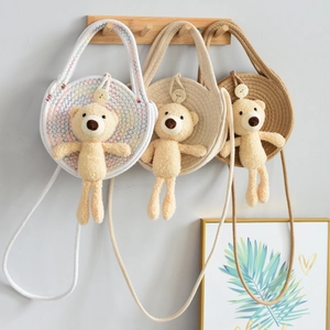 Detailed close-up of colorful woven straw crossbody bags with cute plush bear charms