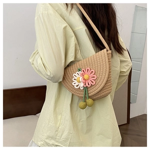 Detail view of woven straw crossbody bag with 3D crochet flowers on yellow shirt