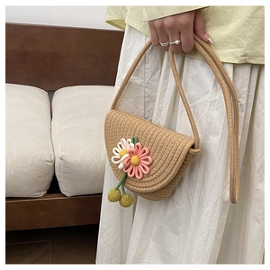 Close-up of handmade woven straw crossbody bag with floral accents and cherry details
