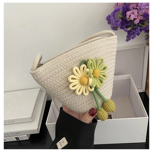 Close-up of cream woven bucket bag featuring floral charms and metal zipper detail