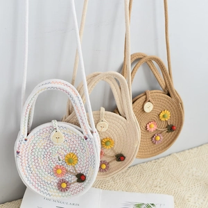Detailed macro of woven straw crossbody bags with floral appliques and ladybug accents