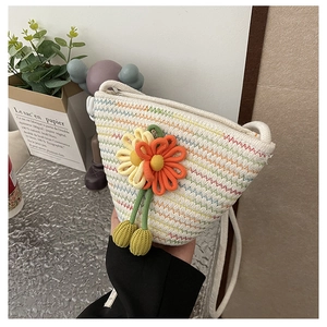 Detailed view of cream woven crossbody bag featuring colorful floral sunflower accents