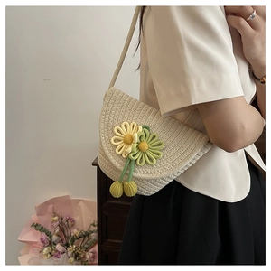 Detailed side view of beige straw crossbody bag with floral weaving and tassels