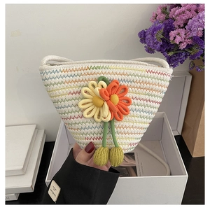 Detailed close-up of handmade straw shoulder bag with colorful embroidery and knit flowers