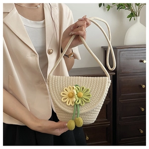Detail of woven straw crossbody bag with daisy floral accents and beaded charms