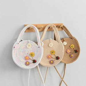 Close-up of three woven straw bags with 3D floral accents hanging on wooden hooks