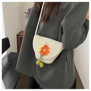 Close-up of hand-woven crossbody bag with colorful flower patterns and green tassels