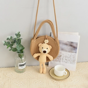 Detail of round straw crossbody bag with cute plush bear pendant in cozy home setting