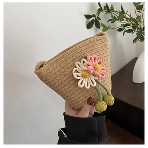 Detail of hand-woven straw bag featuring 3D floral accents and yellow pompom charms
