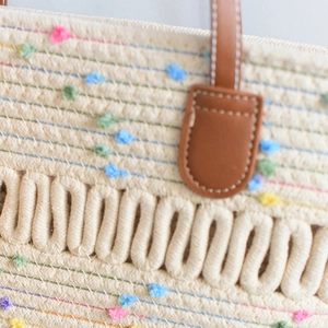 Detail of hand-woven tote bag texture with colorful pom-poms and wave knitting patterns