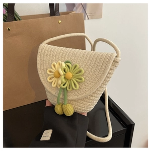 Close-up of beige woven crossbody bag with detailed yellow and green floral accents