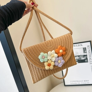 Detail of hand-woven straw crossbody bag featuring colorful 3D crochet flower decorations