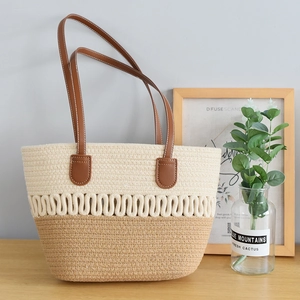Detail of two-tone woven tote bag with brown leather straps and contrast stitching