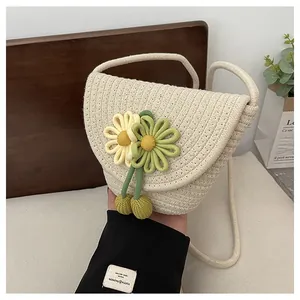 Detail of hand-woven crossbody bag featuring decorative crochet flowers and warm rustic texture