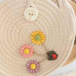 Detail of woven straw bag with handmade fabric daisy flowers and wooden button decoration