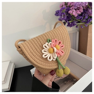 Close-up of semi-circular straw crossbody bag with handmade knit flowers and thin strap