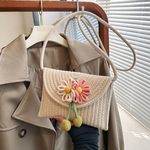 Detail of woven straw crossbody bag with handmade floral accents and elegant rope strap