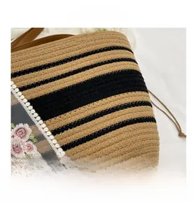 Détail du sac bandoulière en paille avec rayures noires et broderies de fleurs