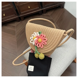 Close-up of hand-woven straw bag featuring 3D crochet flowers and cherry charms