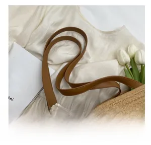 Détail d'un sac cabas en paille tissée avec broderie dentelle et anse en cuir
