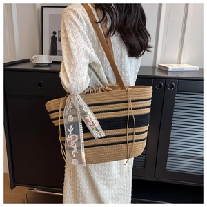 Détail du sac cabas en paille tissé à la main avec rayures noires et foulard en dentelle