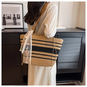 Détail du sac cabas en paille tressé avec rayures noires et écharpe en dentelle florale