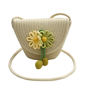 Detail of hand-woven straw crossbody bag featuring 3D fabric flower accents and tassels