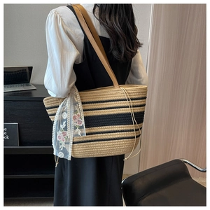 Détail du sac cabas en paille tissé avec motif rayé, foulard en dentelle et anses cuir