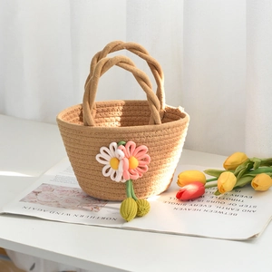 Détail d'un sac à main en coton tissé kaki avec fleurs en tricot rose sur table blanche