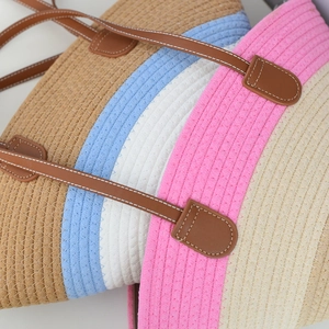 Close-up of woven cotton tote bag featuring colorful stripes and faux leather handles