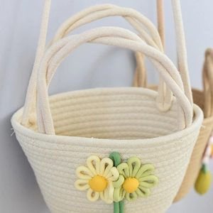 Detail of hand-woven cream cotton rope bag with decorative floral accents and dual handles