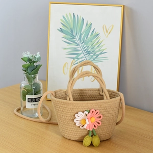 Close-up of handmade woven straw bag with pink flowers and decorative green charms