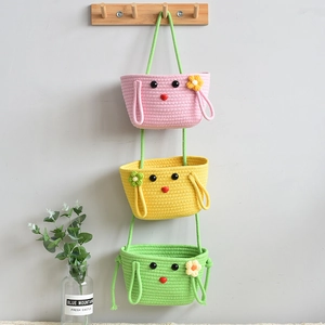 Detail of three-tier cartoon woven storage baskets in pink, yellow and green colors