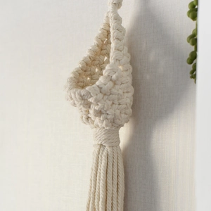 Close-up of hand-woven teardrop macrame plant hanger with long fringe and cotton knots