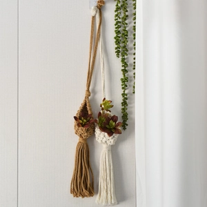 Detail of handmade macrame hanging planters with long tassels in boho style interior