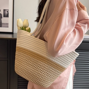 Detailansicht der zweifarbigen Strohtasche mit Textur und eleganten Tulpenverzierungen