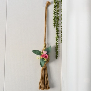 Detail of bohemian hand-woven cotton rope wall hanging with pink roses and tassels